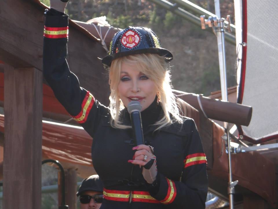 Singer Dolly Parton holding a guitar on stage