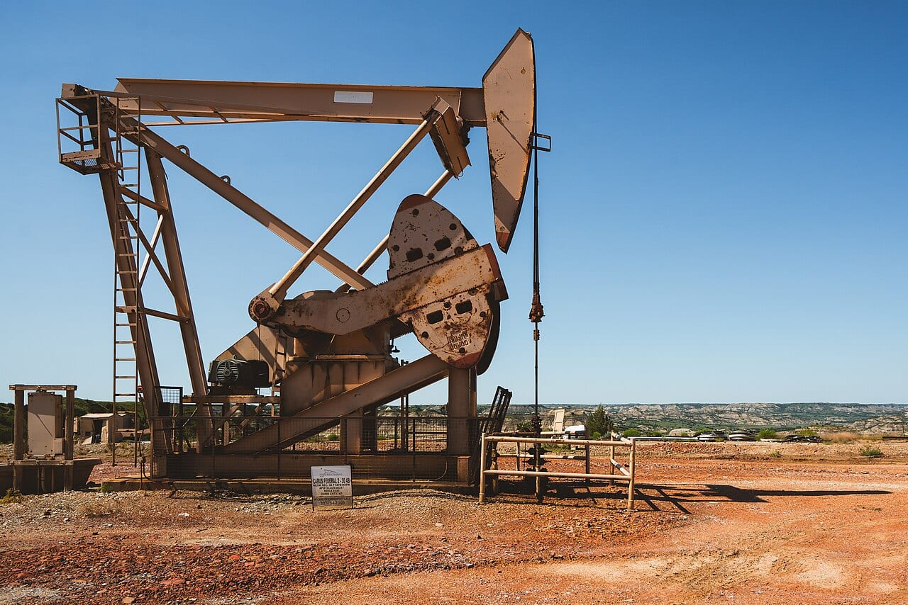 An oil pump jack standing in a dry open field